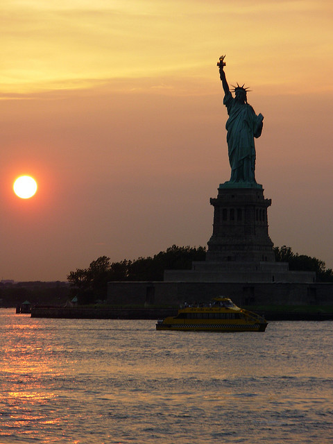 Statue of Liberty with water taxi at sunset, New York, USA